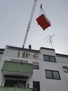 Tiefgaragensanierung München-Giesing: hier hievt unser Kran einen Schuttcontainer über das Gebäude