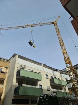 Tiefgaragensanierung München-Giesing: der Kran im Einsatz - hier hievt er unseren Kleinbagger über das Gebäude